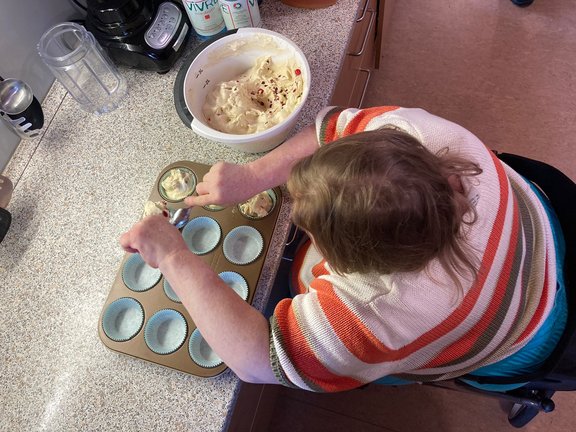 Johannisbeermuffin Frau füllt Teig in Förmchen für Johannisbeermuffins