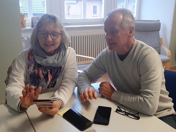 Handysprechstunde Eine Frau probiert etwas am Smartphone aus, ein Mann schaut zu