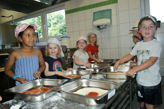 Kinder kochen Kinder bestreichen Pizzateig mit Soße